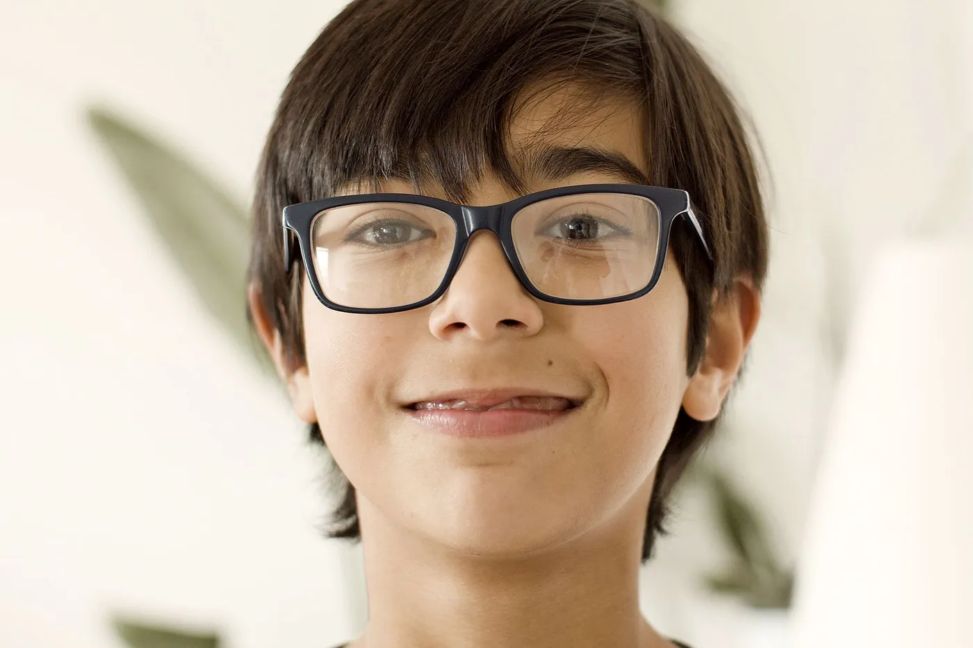 Jeune garçon souriant, portant des lunettes de vue noires