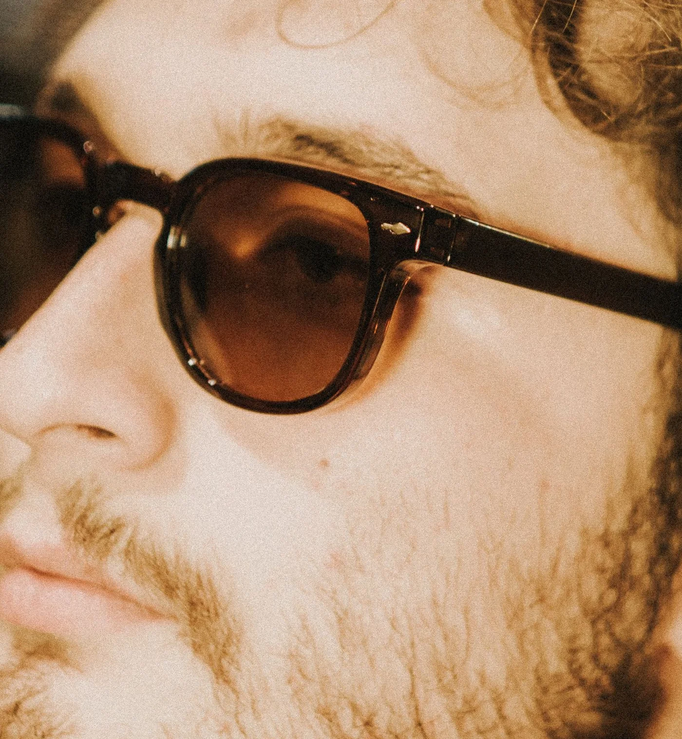 Gros plan sur des lunettes de soleil à monture écaille et verres ambrés, portées par un homme