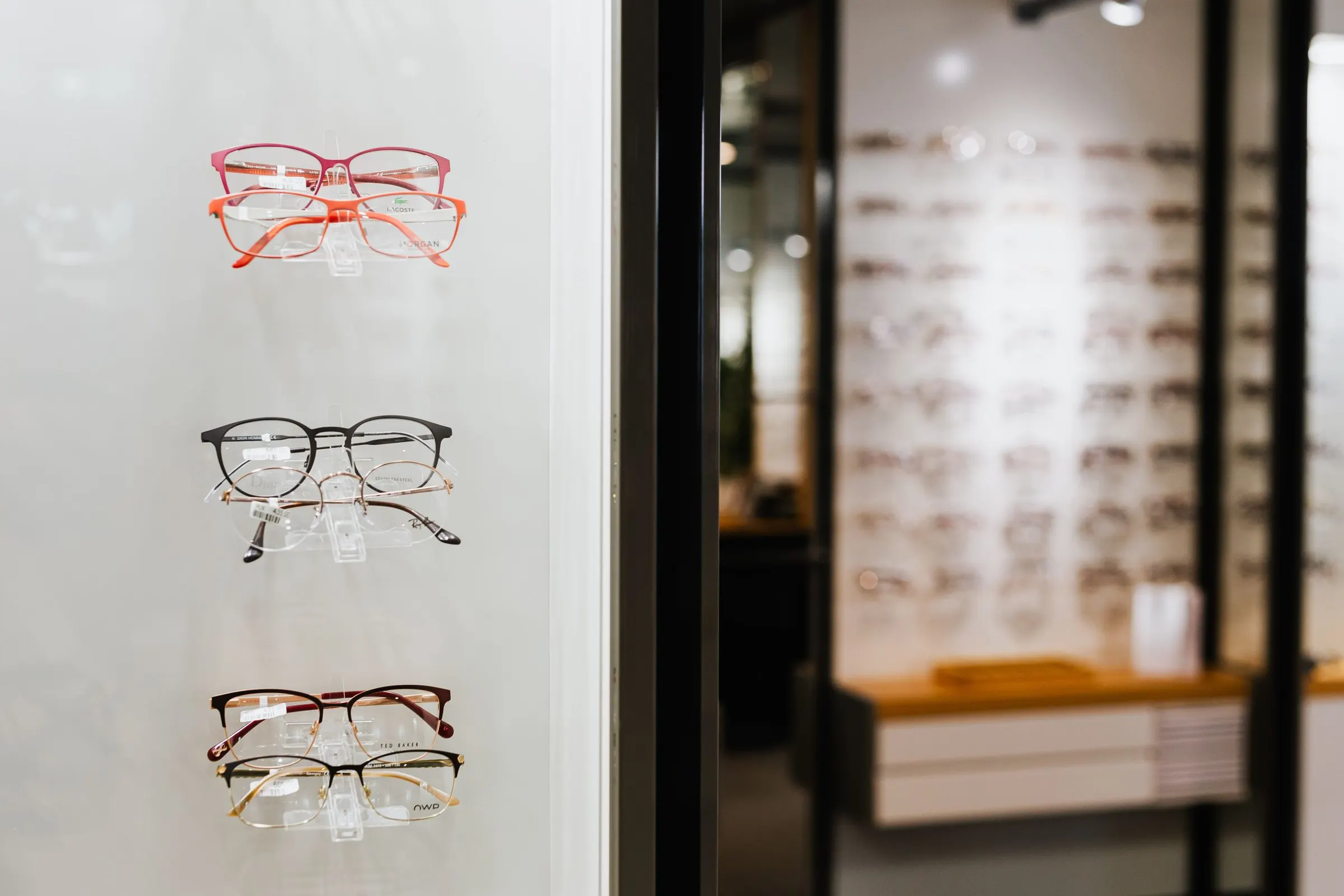 Montures de vue posées sur des étagères en verre dans une boutique d'optique