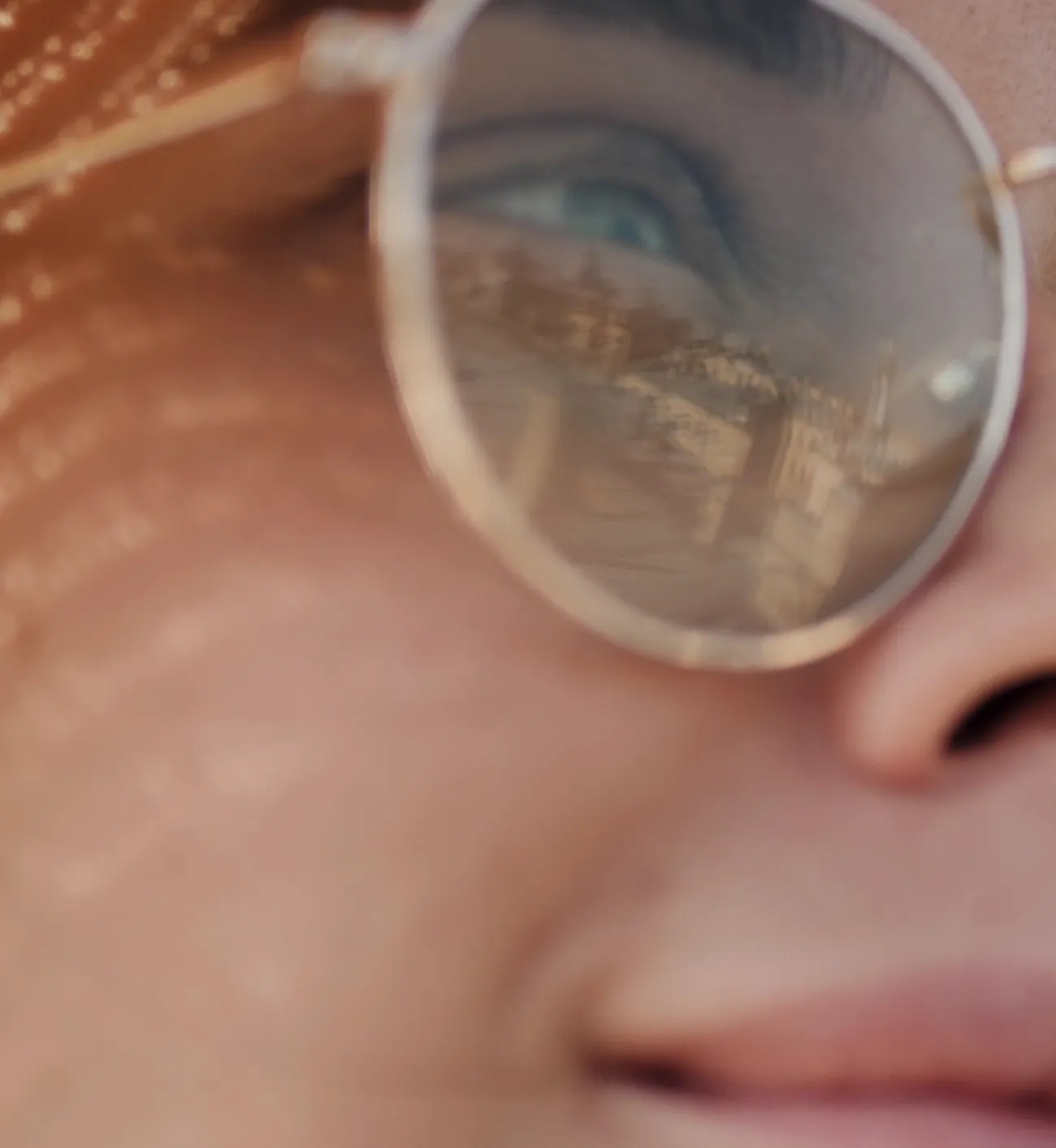 Femme portant une monture ronde dorée, la lumière du soleil sur le visage