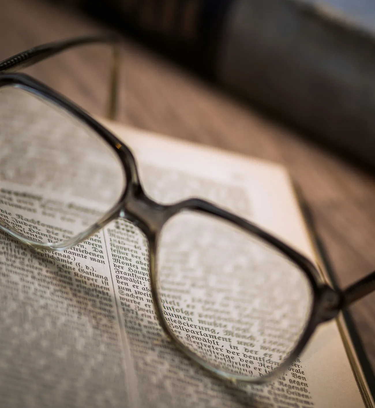 Lunettes de vue posées sur un livre ouvert, le texte vu à travers les verres